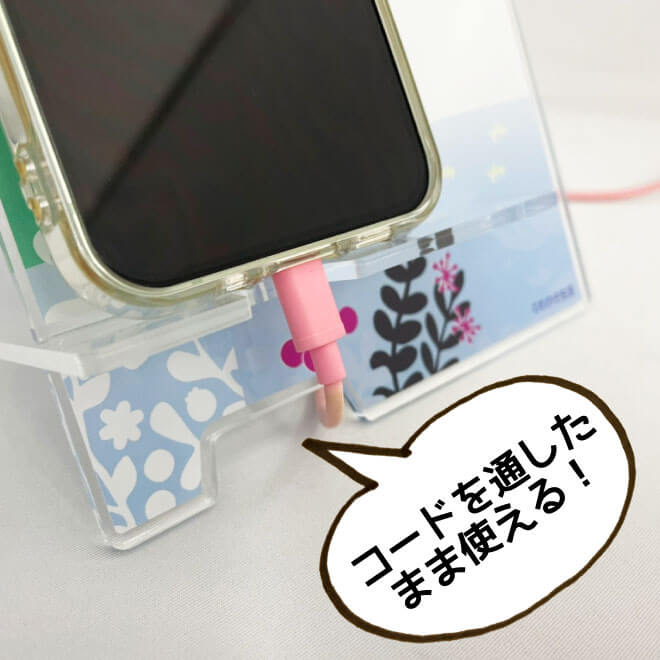 コードを通したまま充電できる。コードを通せるのですっきり。充電しているスマホをスマホスタンドに置いて使用している画像