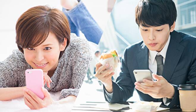 スマホを見て楽しんでいる女性と食事をしながらスマホを確認する男性の画像